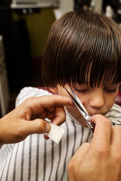 Niño de alto ángulo cortándose el pelo