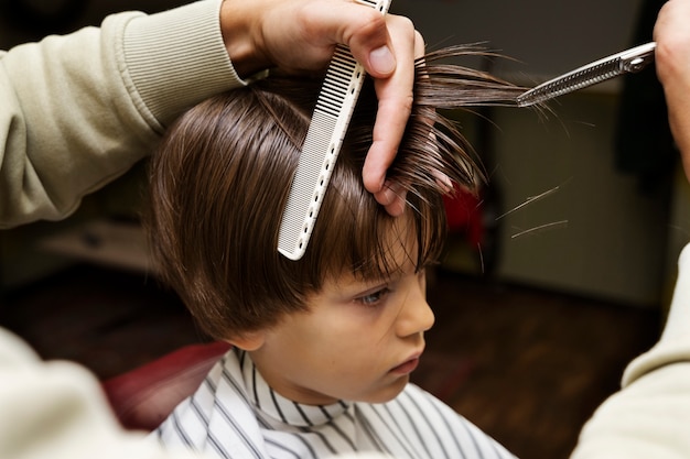 Niño de alto ángulo cortándose el pelo