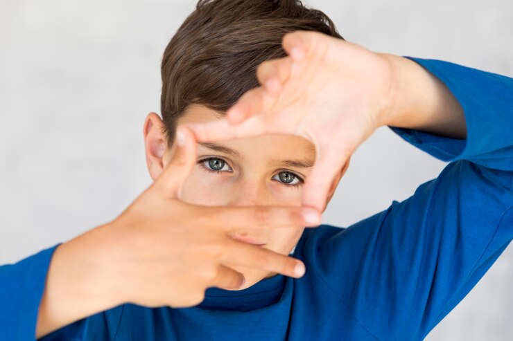Foto gratuito niño de alto ángulo haciendo un marco con los dedos