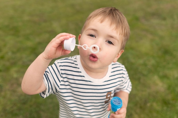 Foto gratuita niño de alto ángulo jugando con soplador de burbujas