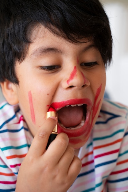 Niño de alto ángulo con lápiz labial rojo