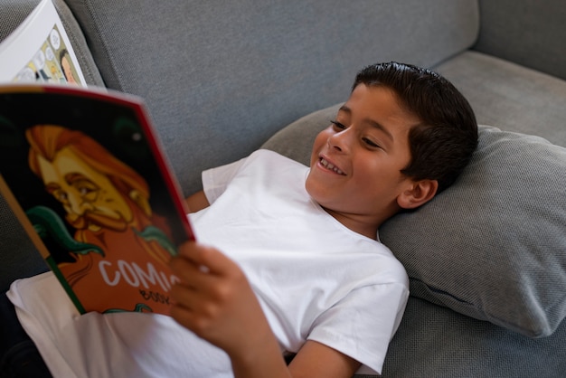 Niño de alto ángulo leyendo cómics en casa