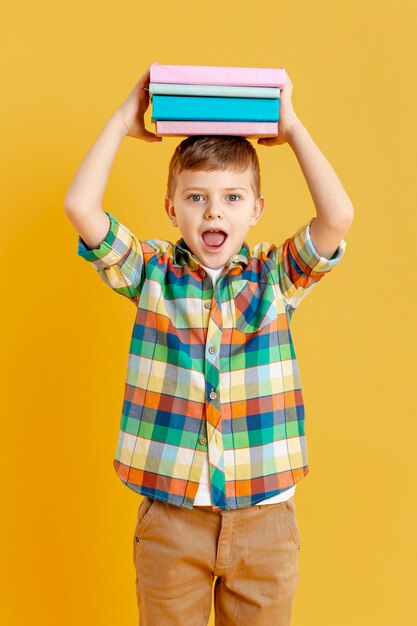 Niño de alto ángulo con libros sobre su cabeza