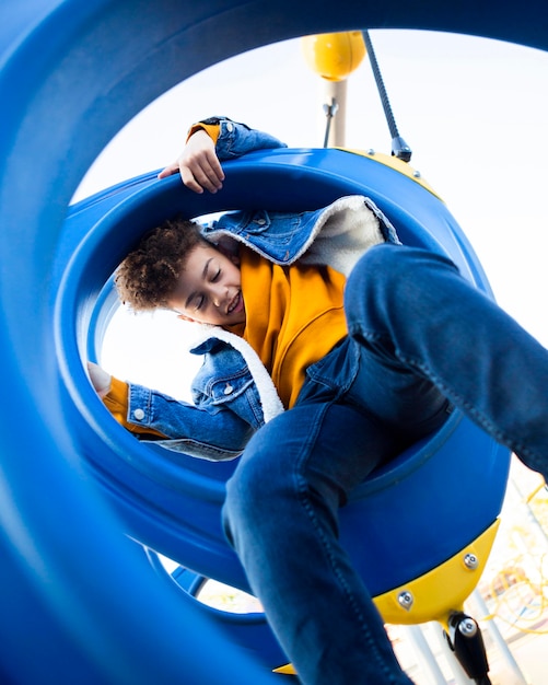 Niño de ángulo bajo divirtiéndose en el patio de recreo