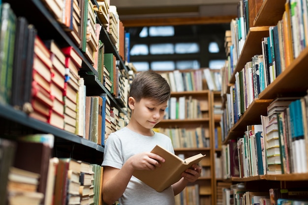 Niño de ángulo bajo en la lectura de la biblioteca