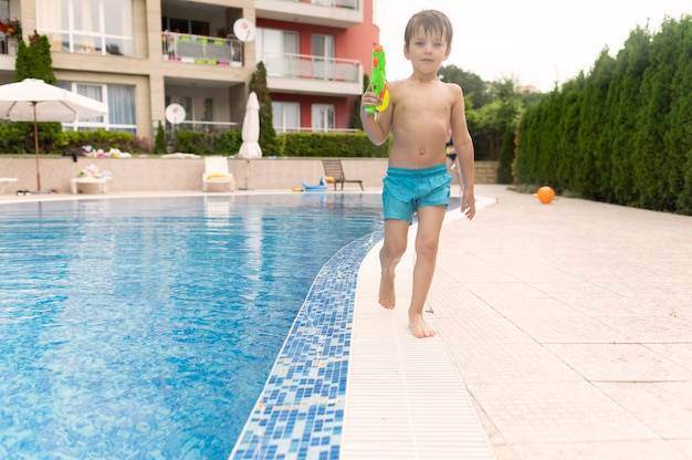 Niño de ángulo bajo con pistola de agua