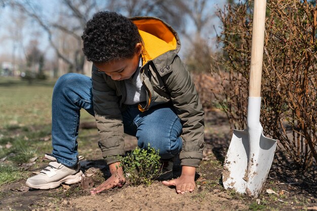 Niño aprendiendo a plantar un árbol.