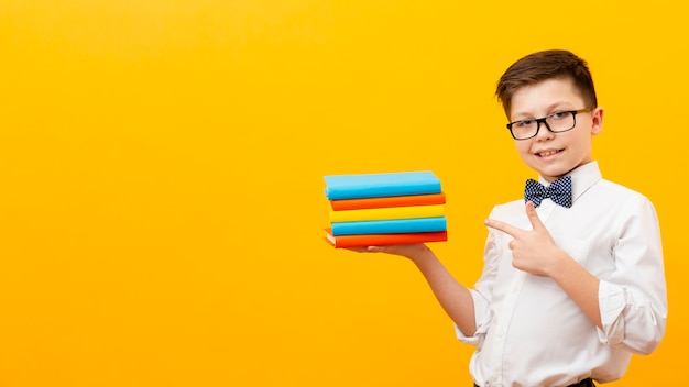 Niño apuntando a la pila de libros