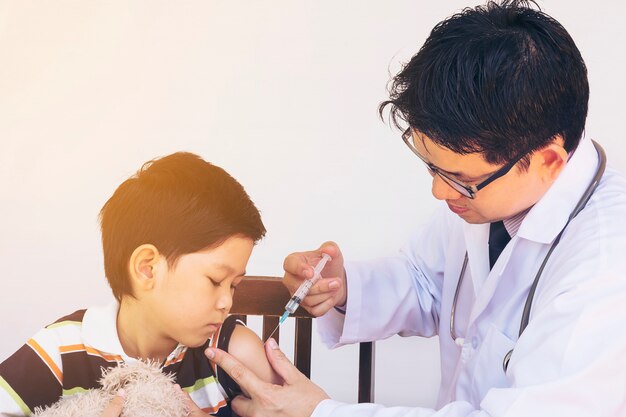 Niño asiático enfermo siendo tratado por médico masculino