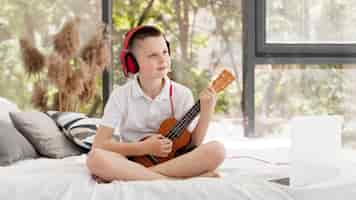 Foto gratuita niño con auriculares jugando tiro largo ukelele