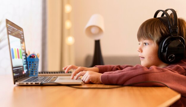 Niño con auriculares que asisten a la escuela virtual