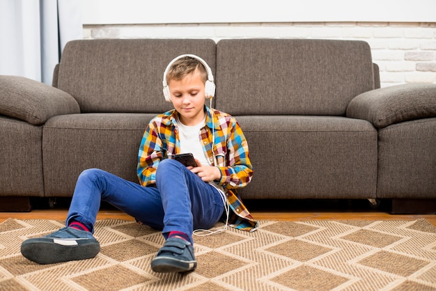 Foto gratuita niño con auriculares usando smartphone