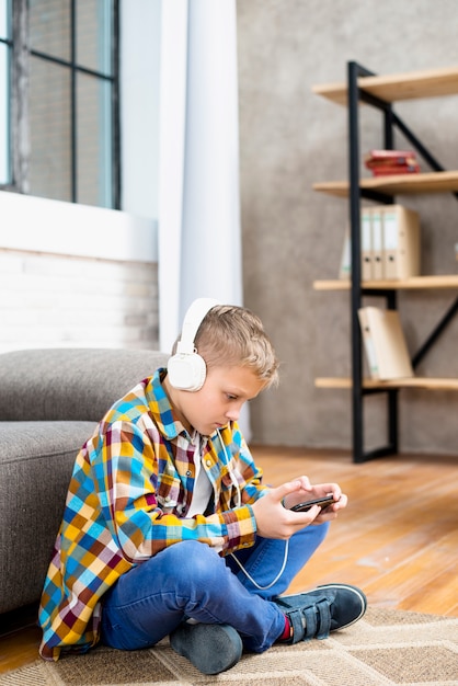 Foto gratuita niño con auriculares usando smartphone