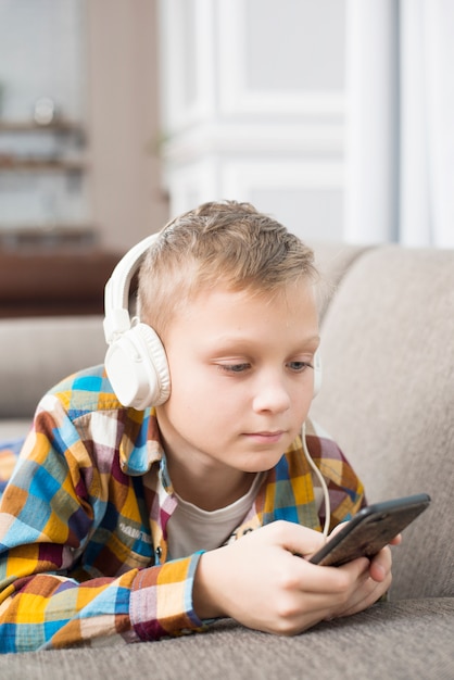 Foto gratuita niño con auriculares usando smartphone