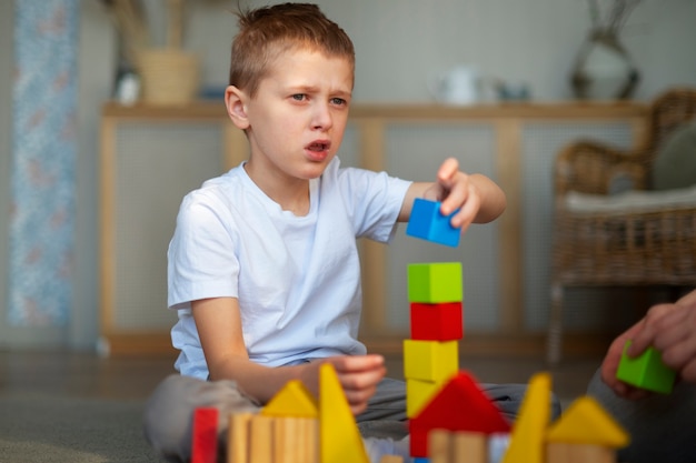 Foto gratuita niño autista joven jugando con juguetes en casa