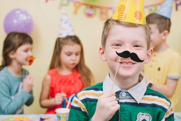 Niño con bigote de papel en la fiesta de cumpleaños