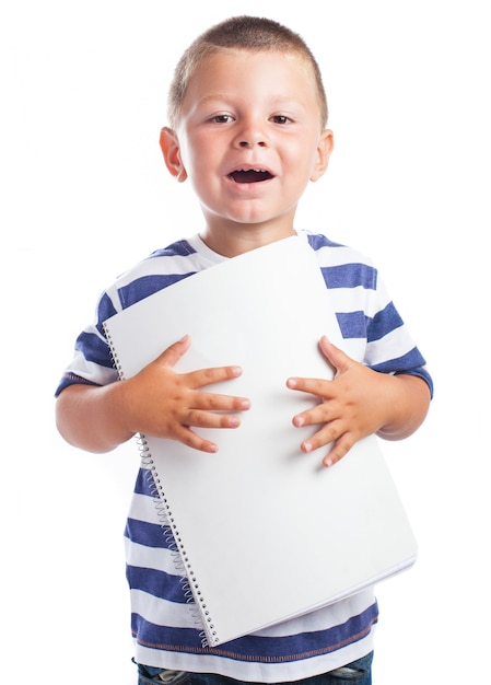 Foto gratuita niño con la boca abierta y una libreta en blanco