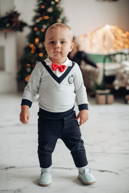 Foto gratuita niño bonito en traje camina a la sala de estar en casa