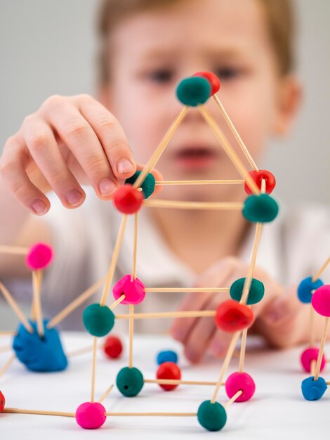 Niño borroso jugando con colorido juego de átomos