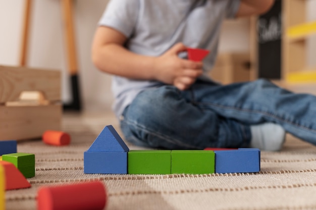 Foto gratuita niño borroso jugando en el piso con juguetes