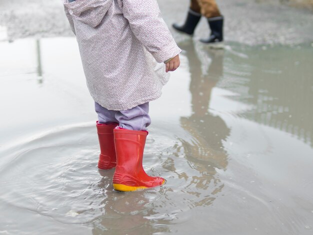 Niño con botas y sentado en el agua