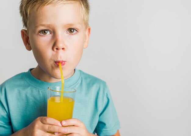 Niño de cabello rubio bebiendo jugo