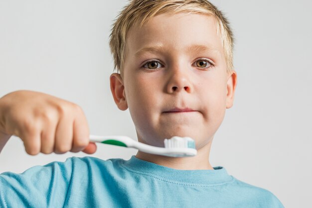 Niño de cabello rubio con cepillo de dientes