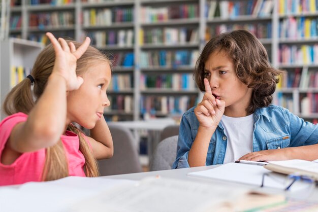 Niño callando a una niña en la biblioteca