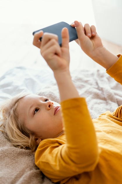 Niño en la cama jugando en el móvil