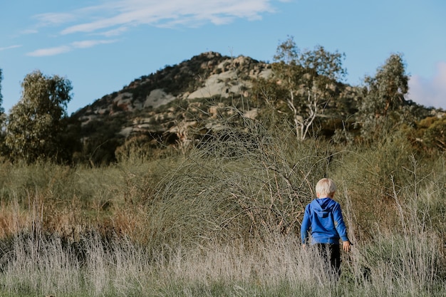 Niño caminando en el campo con un paisaje montañoso detrás