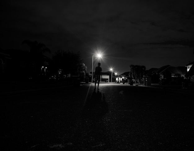 Niño caminando solo por la noche bajo las luces de la calle