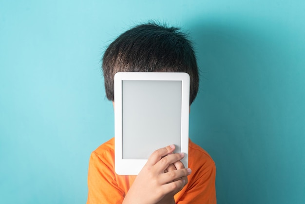 Niño en camiseta naranja con lector de libros electrónicos