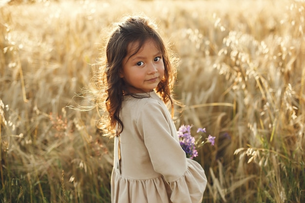 Niño en un campo de verano. Niña con un lindo vestido marrón.