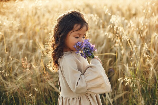 Niño en un campo de verano. Niña con un lindo vestido marrón.