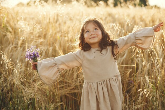 Niño en un campo de verano. Niña con un lindo vestido marrón.