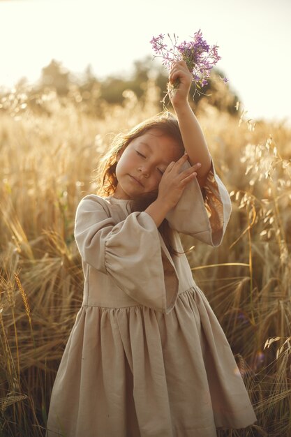 Niño en un campo de verano. Niña con un lindo vestido marrón.