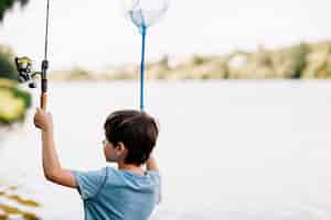 Foto gratuita niño con caña de pescar y red cerca del lago