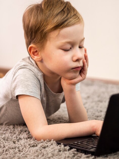 Niño cansado jugando en la computadora portátil