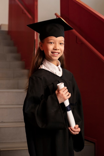 Foto gratuita niño celebrando la graduación de jardín de infantes