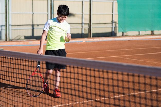 Niño celebrando la victoria de un juego de tenis