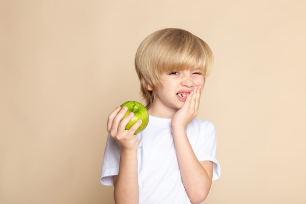 niño chico lindo con manzana verde en camiseta blanca en rosa