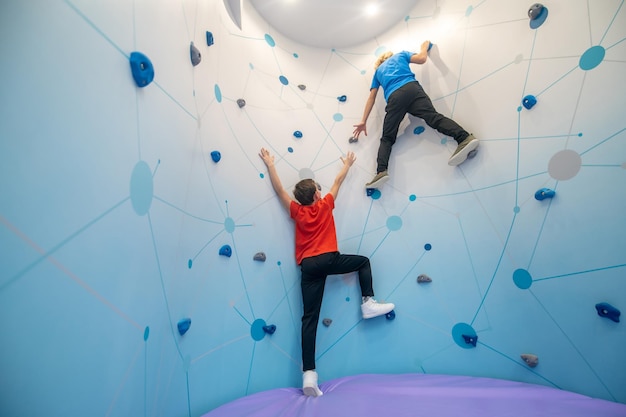 Foto gratuita niño colgado en la pared prestando una mano a un amigo