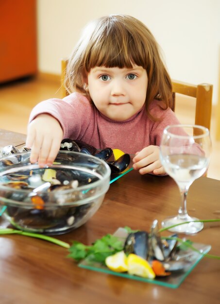 Niño come mejillones en casa