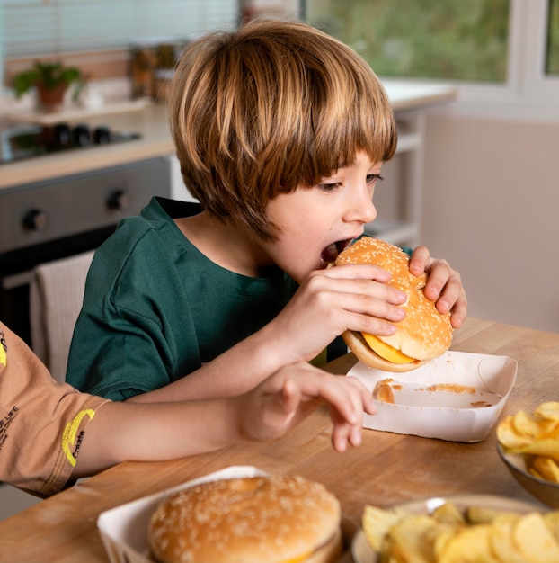 Niño comiendo hamburguesas en casa