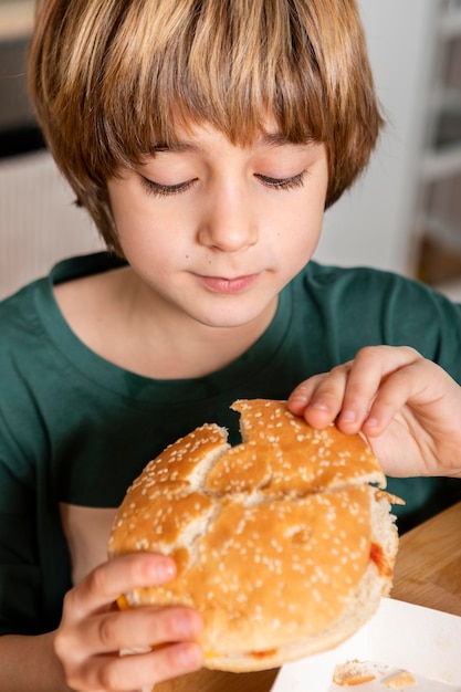 Niño comiendo hamburguesas en casa