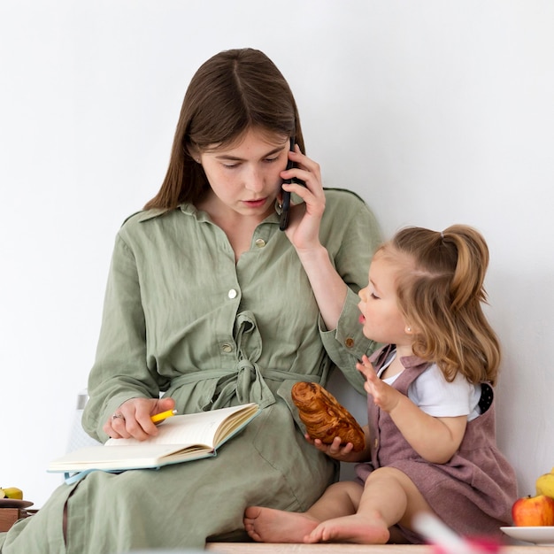 Niño comiendo con madre trabajando