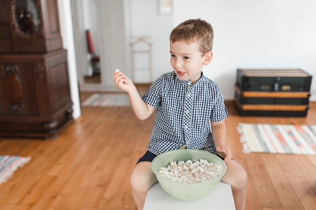 Niño comiendo palomitas en casa