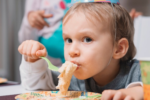 Niño comiendo pastel en la fiesta de cumpleaños