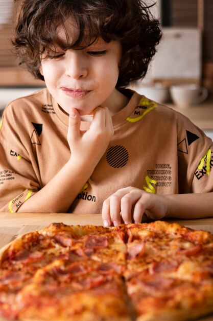 Niño comiendo pizza en casa