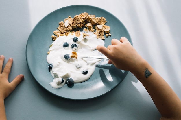 Foto gratuita niño comiendo yogur con bayas